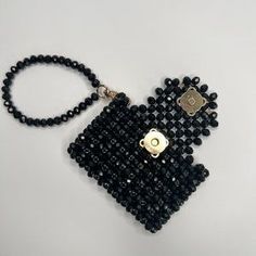 a black beaded purse hanging on a white surface with a gold clasp and keychain