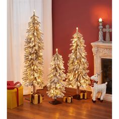 three small christmas trees with lights on them in front of a fire place and fireplace