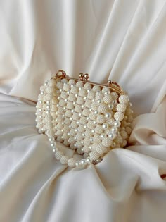 🌟 Elevate your style with this exquisitely crafted handbag adorned with pearl details. 🌟 Handcrafted with care, this bag is designed to add a touch of sophistication to every moment. The elegance of the pearl embellishments sets this bag apart, transforming it into a unique accessory. 🌸 Why Choose This Bag? 🌸 More than just an accessory, this bag is an opportunity to reflect your style and grace. Whether for a special event or to enhance your daily chic, this pearl-adorned bag complements ev Beige Clutch Evening Bag With Pearl Handle, Cream Evening Bag With Pearl Handle, Beige Pearl Evening Bag For Events, Pearl Evening Bag With Pearl Handle For Wedding Guest, Pearl White Wedding Shoulder Bag With Pearl Handle, Beige Pouch Clutch With Pearl Handle, Pearl Handheld Shoulder Bag For Weddings, Handheld Pearl Shoulder Bag For Wedding, Pearl White Shoulder Bag With Pearl Embroidery For Wedding