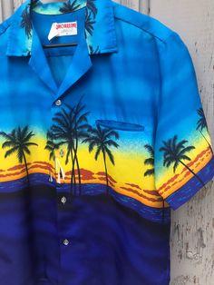 "Excellent vintage condition. No stains, no holes, no odors. Tag size M. Fits like a Men's roomy Medium. Laying flat: 22 1/2\" Pit to Pit 27\" Top to Bottom Awesome 70s tropical shirt by Shoreline, made in Hawaii. Super soft and lightweight button up shirt, made of polyester. Great for a hot day at the beach!" Blue Summer Camp Shirt For Beach, Blue Tropical Shirt For The Beach, Tropical Blue Shirt For The Beach, Tropical Blue Shirt For Beach, Vintage Hawaiian Shirt For Beach With Relaxed Fit, Vintage Hawaiian Shirt For Beach In Relaxed Fit, Vintage Hawaiian Shirt For Beach, Relaxed Fit, Blue Camp Shirt With Graphic Print For Beach, Yellow Hawaiian Shirt With Tropical Print For Beach