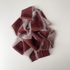 a pile of red and white scarves laying on top of each other in front of a white wall