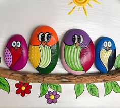 five painted rocks sitting on top of a branch