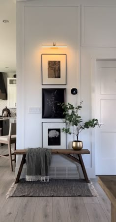 a living room with white walls and pictures on the wall, plants in vases