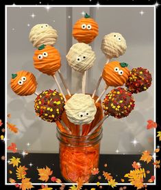 a jar filled with cake pops covered in white frosting and decorated to look like pumpkins