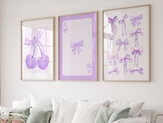 three framed pictures hang on the wall above a couch in a living room with white furniture