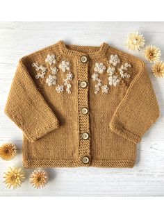 a knitted sweater with flowers on the front and back, sitting next to it