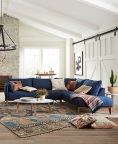 a living room with blue couches and rugs in front of a brick wall