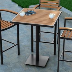 an outdoor table and chairs set up on a stone patio with grass in the background