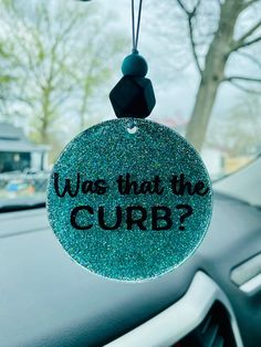 an ornament that says, was that the curb? hanging on a car dashboard