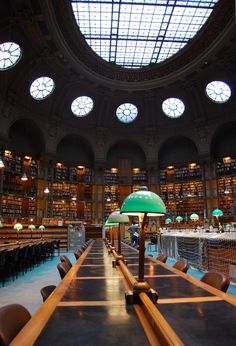 the inside of a library with tables, chairs and an umbrella in front of them