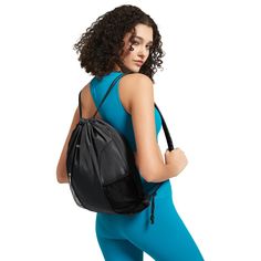 a woman with curly hair is carrying a black backpack