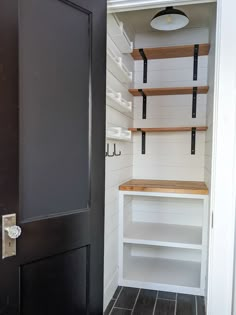 an empty pantry with shelving and shelves on the wall, next to a black door