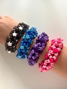 three different colored bracelets on someone's arm, one with hearts and the other with stars