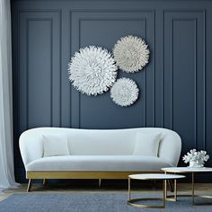 a living room with blue walls and white furniture on the floor, along with three circular wall art pieces