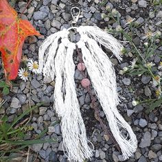 a piece of white string is laying on the ground next to some rocks and flowers