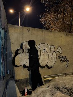 a man standing next to a wall covered in graffiti