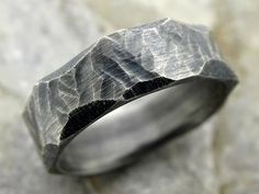 a silver ring with mountains on it sitting on top of a stone slabd surface