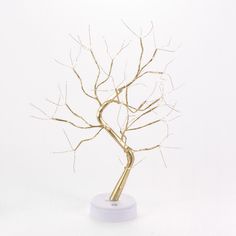 there is a gold tree with no leaves on the white stand and one branch has been cut out