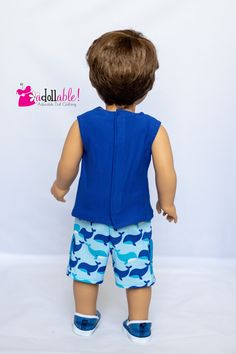 a little boy doll wearing blue shorts and a shirt with camo print on it