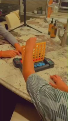 two children are playing with an abacus at the table in front of their mother