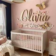 a baby's room decorated in pink and white with butterfly decorations on the wall