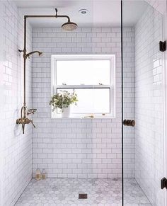 a white tiled bathroom with a window and shower