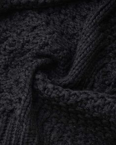 the texture of a knitted blanket is shown in dark grey tones, as well as black and white colors