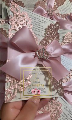 a person holding up a pink and gold wedding card with flowers on it's side