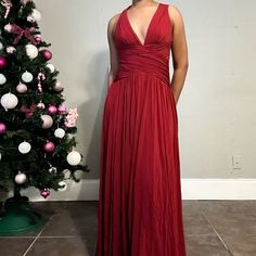 a woman in a long red dress standing next to a christmas tree with ornaments on it