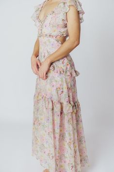 We think the gorgeous Millie Maxi Dress from ASTR is fit for a princess. It's all flowers and ruffles and utterly romantic, perfect for a special vacation dinner, or for when you want to RSVP "elegant" to a spring wedding or shower. This dress doesn't skimp on the feminine details, and deserves a place of honor in your closet! FIT: Runs true to size. Bust is fitted, with a low neckline and bodice cut-outs. MATERIAL: GARMENT DETAILS: Floral chiffon maxi dress, with a plunging V-neckline, multi-tiered ruffled sleeves, and side cut-outs under the bust. Features a full, flowy skirt with ruffle accents, a smocked back panel, and a back self-tie detail at the shoulders. SIZE GUIDE: XS (00-0) / S (2-4) / M (6-8) / L (10-12) MODEL DETAILS: ﻿Heather is wearing size S. Mackenzie - Size S Heather - S Flirty Dresses With Ruffled Straps For Garden Party, Flirty Ruffled Dress For Garden Party, Pink Midi Dress With Ruffled Straps For Garden Party, Maxi Length Ruffled Skirt Dress For Garden Party, Elegant Dress With Ruffled Skirt For Garden Party, Feminine Ruffled Midi Dress For Garden Party, Flowy Midi Dress With Ruffled Straps For Garden Party, Feminine Ruffled Dress For Garden Party, Elegant Tiered Floral Dress