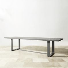 a long table sitting on top of a tiled floor next to a white wall in an empty room