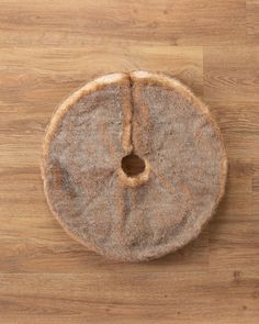 a cat bed with a hole in the middle on a wooden floor, viewed from above