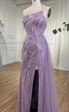 This enchanting gown in a delicate lavender hue exudes elegance and sophistication. It features intricate bead and feather embellishments, adding texture and a touch of whimsy. The gown is backless, offering a bold and alluring look. A side drape creates a soft, flowing effect that enhances the overall silhouette. This stunning piece is perfect for a glamorous evening event or a special occasion where you want to leave a lasting impression. Production time is between approx 6-8 weeks. * Sizing - Elegant Lavender Tulle Evening Dress, Purple Sequined Gown For Debutante Ball, Purple Embellished Tulle Gown, Purple Embellished Gown For Debutante Ball, Elegant Lavender Evening Dress For Debutante Ball, Glamorous Embellished Purple Gown, Glamorous Purple Embellished Gown, Lavender Gowns Elegant, Lavender Gowns