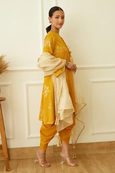 Ochre kurta with gold foil floral print and gota detail. Paired with tulip dhoti pant and dupatta.
Components: 3
Pattern: Printed
Type Of Work: Floral,Foil
Neckline: Keyhole
Sleeve Type: Bell
Fabric: Cotton Silk, Handwoven Kota Doriya
Color: Yellow
Other Details: 
Gota detail
Kurta front drawstring
Occasion: Sangeet,Mehendi and Haldi - Aza Fashions Gold Palazzo Set With Traditional Drape For Eid, Gold Palazzo Set For Eid With Traditional Drape, Gold Palazzo Set With Zari Work Traditional Drape, Gold Palazzo Set With Dupatta For Eid, Festive Gold Palazzo Set Traditional Drape, Gold Anarkali Palazzo Set With Traditional Drape, Gold Anarkali-style Palazzo Set, Gold Embroidered Palazzo Set For Festivals, Gold Semi-stitched Palazzo Set With Traditional Drape