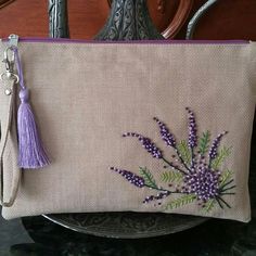 a purse with purple flowers on it and a tassel hanging from the front, sitting on a table