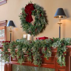 a christmas mantle with wreaths and candles on it