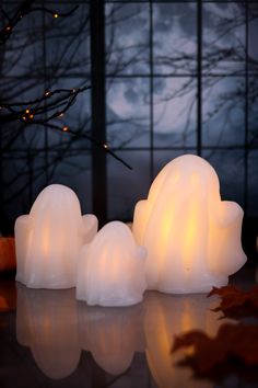 three lit candles sitting next to each other in front of a window with leaves on the ground