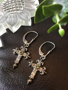 "Earrings ~, Cross Dangle Peridot Cabochon Artist Misti Martin Mystical Madness Cross Length: 7/8\" Cross Width: 5/8\" Sterling Silver Gold wash Cross Tips Peridot is associated with strength and balance, it is believed to bring peace, health, and rest - by harmonizing the mind and body. It is also thought to boost creativity and improve your mood. \"The inspiration for the jewelry comes from my fascination with the many natural resources that come from earth and sea. I consider jewelry making t Nickel-free Round Peridot Earrings, Elegant Pierced Peridot Jewelry, Nickel-free Spiritual Jewelry For May Birthstone, Nickel-free Green Spiritual Jewelry, Green Nickel-free Spiritual Jewelry, Nickel-free Peridot Elegant Jewelry, Elegant Nickel-free Peridot Jewelry, Elegant Peridot Nickel-free Jewelry, Handmade Peridot Round Earrings