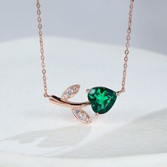 Shaped like a dangling apple adorned with leaves, The centerpiece features a heart-shaped emerald, radiating with the lush green hues of a verdant orchard. Surrounding the emerald, a golden base adds a touch of warmth and elegance. The leaves, crafted from sparkling white sapphires, dance playfully around the emerald, reminiscent of morning dew glistening on lush foliage.    Stone Type: Lab Emerald & White Sapphire  Carat Total Weight: 2.35ct   Style: Natural Inspired  Chain Length: 16" with Emerald Pendant Necklace, Ring Style Guide, Emerald Necklace Pendant, Design Your Own Ring, Fancy Stones, Morning Dew, Rose Gold Heart, Green Hues, Emerald Pendant