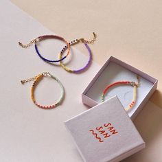 three bracelets are in a box and one is on the table next to it