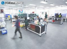 people are walking around in an office with computers on the desks and other equipment