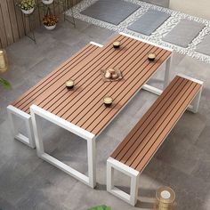 a wooden table with candles on it in the middle of a patio area next to potted plants