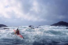 a man riding on top of a kayak in rough ocean water next to small islands