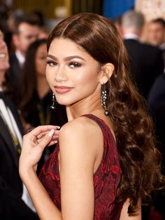 a woman in a red dress with long hair and large earrings on her left shoulder