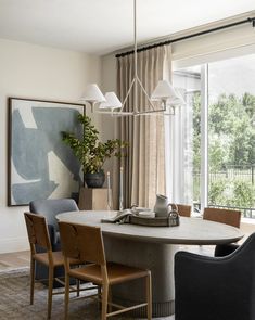 the dining room table is surrounded by four chairs and an art piece on the wall