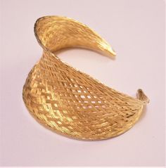 Basket weaved high end luxury strand bracelet bangle cuff vintage gilded gold tone satin smooth bright metal finish open end graduated band golden braided rimmed edge. In excellent never worn vintage condition. Fits most average wrist has a small amount of stretch to the band. Measures 6 inches from end to end, 1 1/2 inches at the widest area of the band and 2 1/2 inches inside. Adjustable Woven Gold Jewelry, Gold Woven Bracelet Jewelry, Adjustable Metal Bangle For Evening, Adjustable Gold Bracelets For Evening, Adjustable Gold Bracelet For Evening, Adjustable Metal Evening Bangle, Gold Cuff Bangle For Evening, Adjustable Gold Woven Bracelet, Adjustable Woven Gold Bracelets