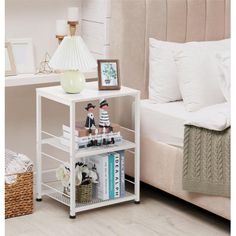 a small white shelf with books and pictures on it next to a bed in a bedroom