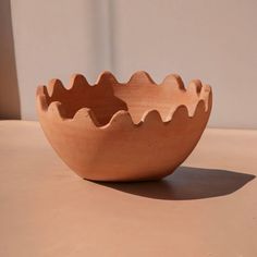 a wooden bowl sitting on top of a table next to a white wall and window