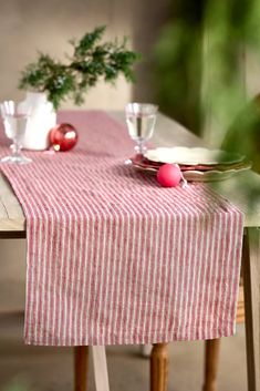 a red and white striped table cloth on a dining room table with plates, silverware and christmas ornaments