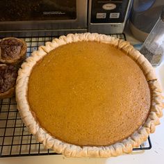 a pie sitting on top of a cooling rack next to an open toaster oven